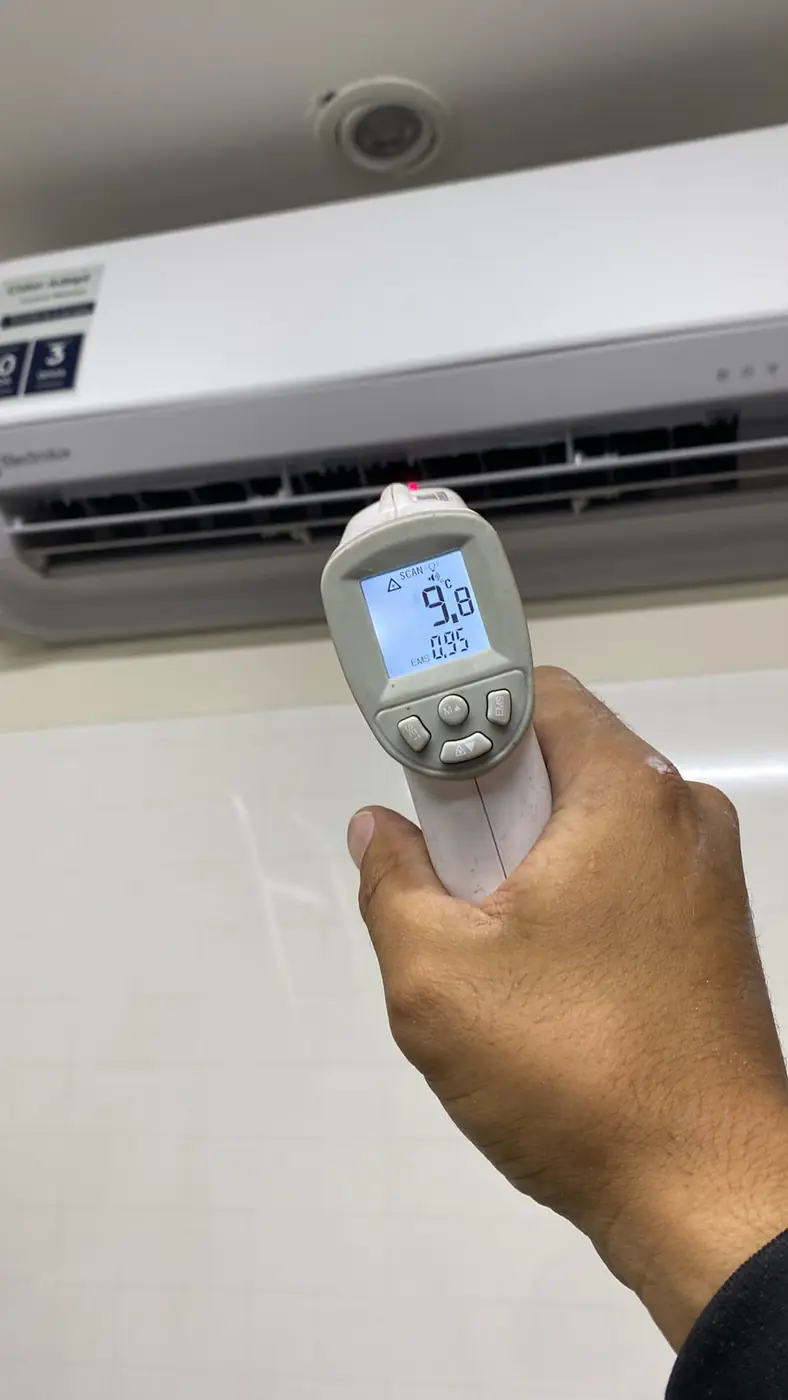 Técnico da Manprev medindo com termômetro a temperatura do ar na saída de um split